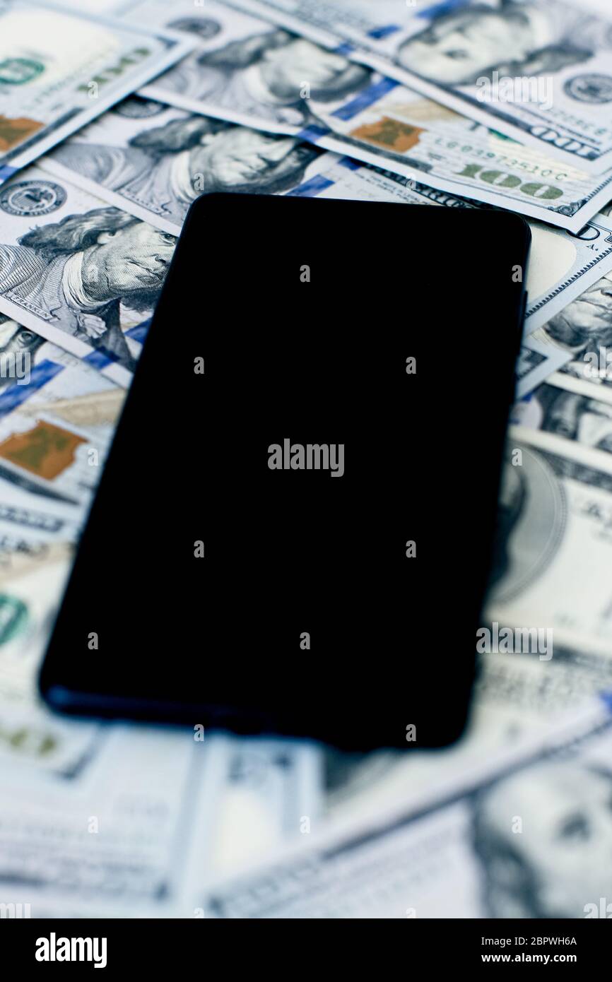 Das Telefon ist auf dem Geld . Geldanlage per Telefon, mobile Zahlungen. Telefon in Dollar. Stockfoto