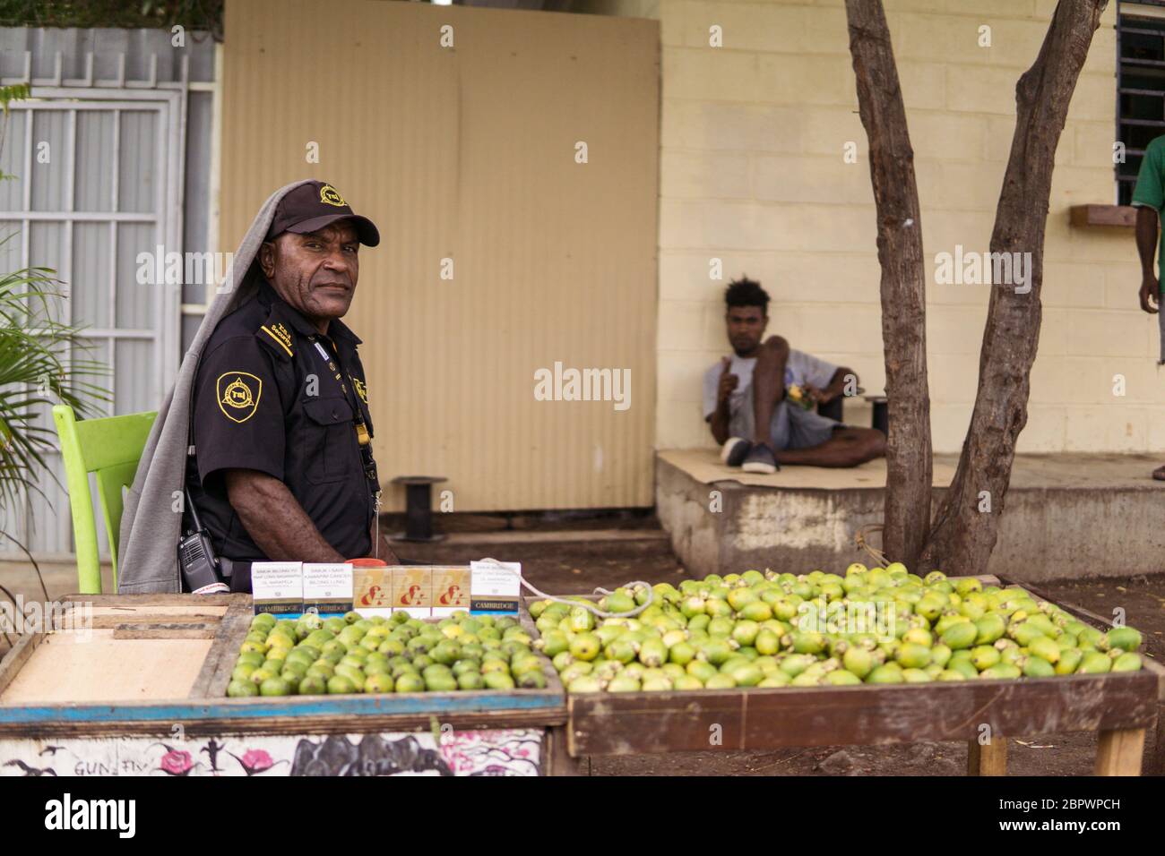 Port Moresby / Papua-Neuguinea: Mann in Sicherheitsgarde Uniform verkauft und konsumiert Betelnüsse, Areca-Nüsse, an einem Straßenstand außerhalb von Port Moresby Stockfoto