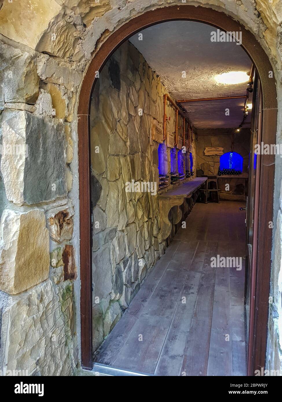 Eingang zum Weinkeller durch eine offene Tür mit einem runden Bogen, Steinmauern Stockfoto