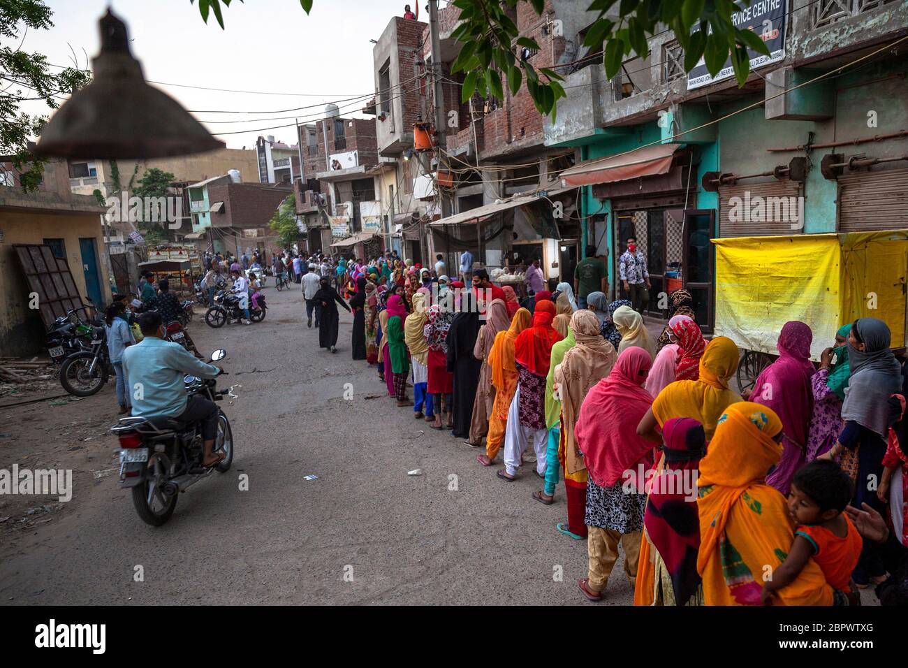 Indische Frauen warten in der kürzlich von Unruhen betroffenen Region Mustafabad in der Schlange, um kostenlose Lebensmittel zu erhalten, als das Land am 14. Mai 2020 in Neu-Delhi, Indien, seine Lockdown-Beschränkung lockert. Die Region Mustafabad gehörte zu den am schlimmsten betroffenen Gebieten, als im Februar in Indiens Hauptstadt Unruhen ausbrachen, weil ein umstrittenes Gesetz zur Änderung der Staatsbürgerschaft von der Regierung der Bharatiya Janata Partei verabschiedet wurde. Mehrere Familien, die wegen Brandstiftung durch Randalierer obdachlos waren, kümmern sich nun um sich selbst inmitten einer landesweiten Sperre, die von der Regierung auferlegt wurde, um die Ausbreitung des Coronavirus im CO einzudämmen Stockfoto
