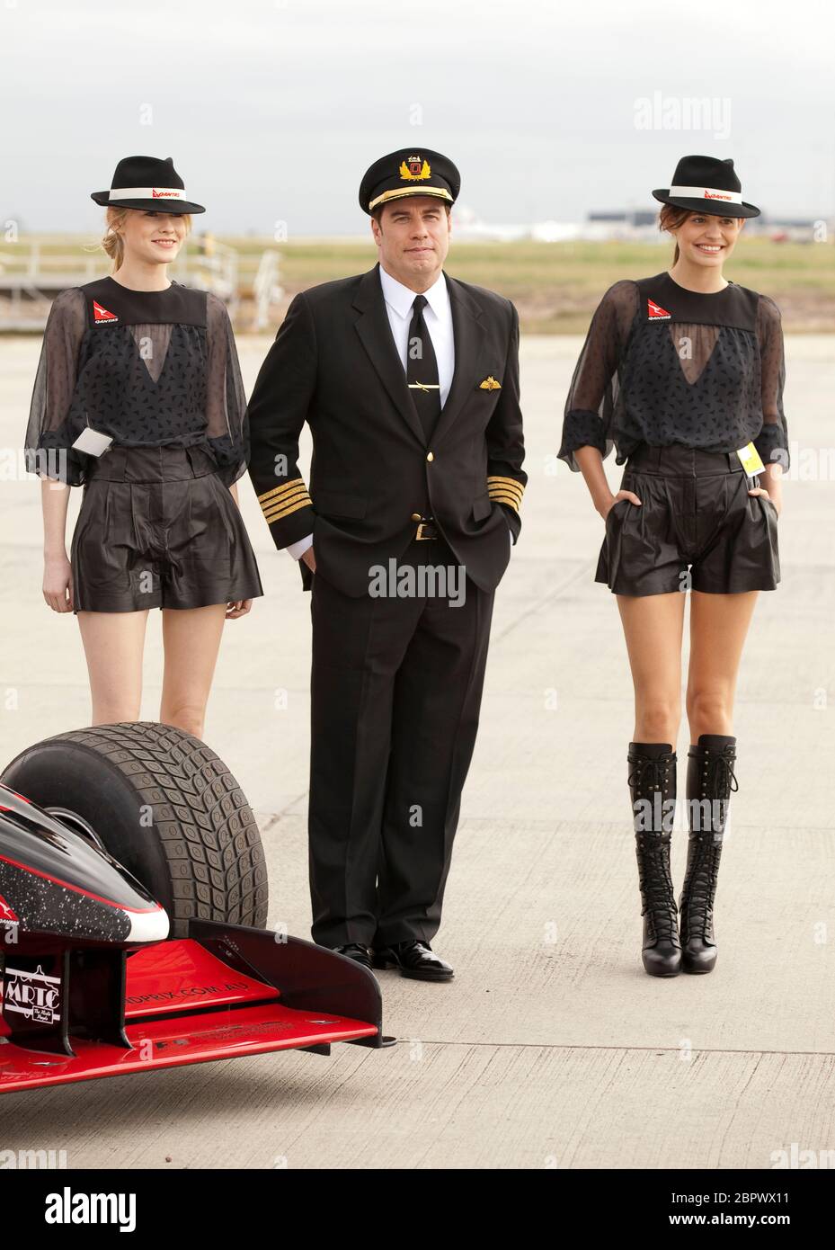 John Travolta mit Models und in Qantas-Pilotenuniform, Flughafen Melbourne, 2010. Stockfoto