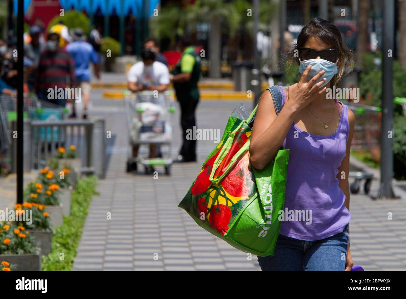 Eine Frau, die eine Maske trägt, trägt Lebensmittel aus dem Supermarkt während der nationalen obligatorischen Quarantäne als Reaktion auf die COVID-19-Pandemie in Lima, Peru. Seit der Einführung der Maßnahme im März hat die Regierung mit der Einhalt der Ausbreitung des Virus vor allem in öffentlichen Bereichen wie Märkten zu kämpfen. 33,931 Menschen wurden infiziert und 943 starben am 29. April 2020. Stockfoto