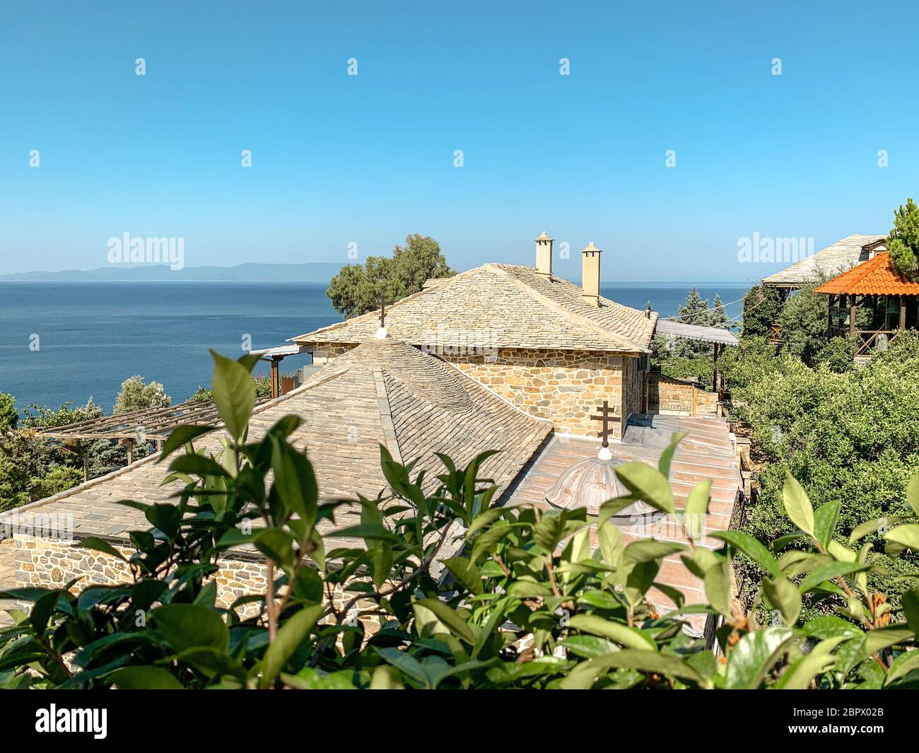 Heiliges Berg Athos. Klostergebäude mit orangefarbenen Fliesen vor dem Hintergrund des Meeres bedeckt Stockfoto