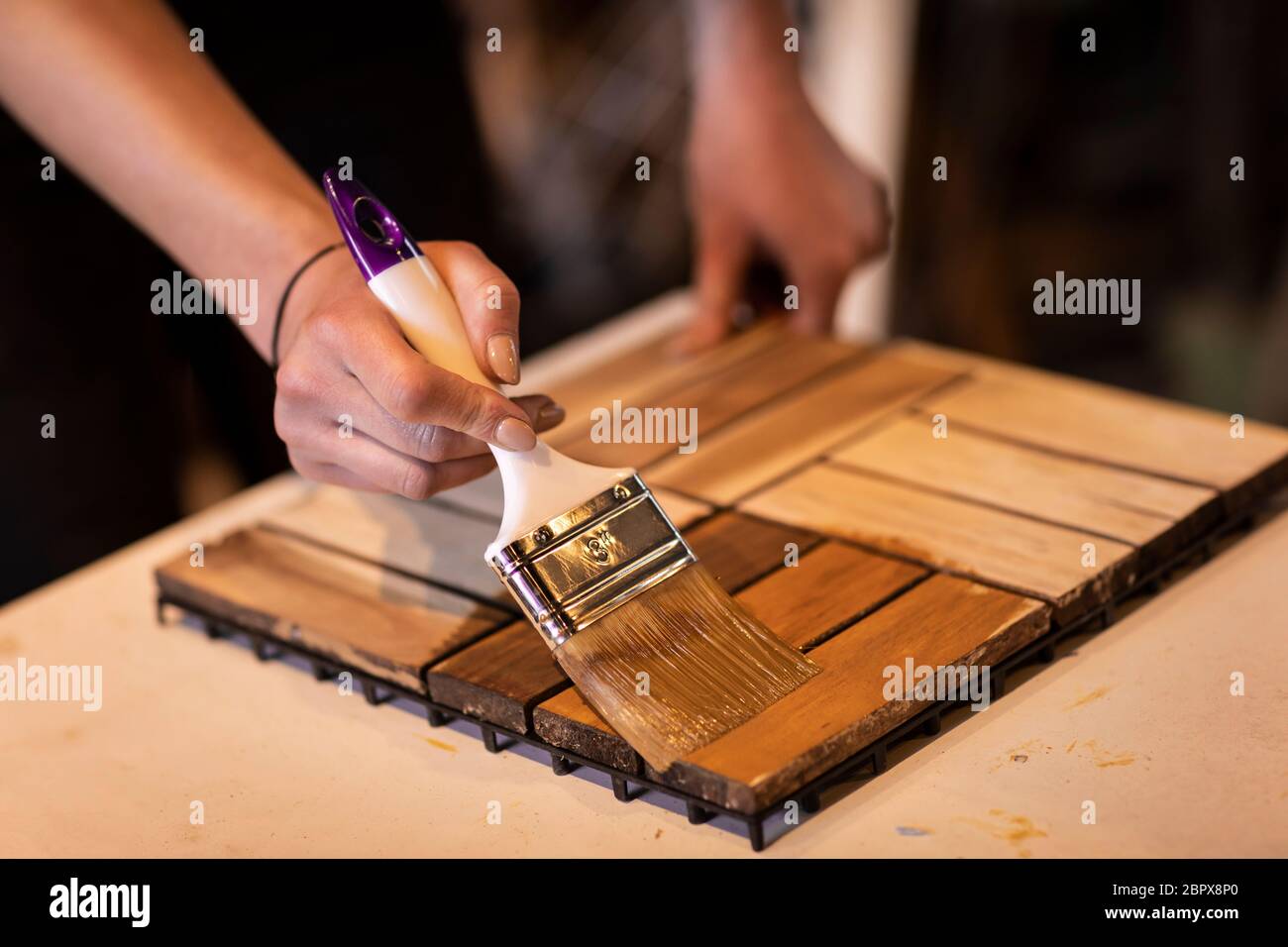 Eine Frau, die eine Holzplatte von Hand einölt. Tun Sie es sich lästige Arbeit von einem Mädchen mit Schutzöl auf Holz Stockfoto