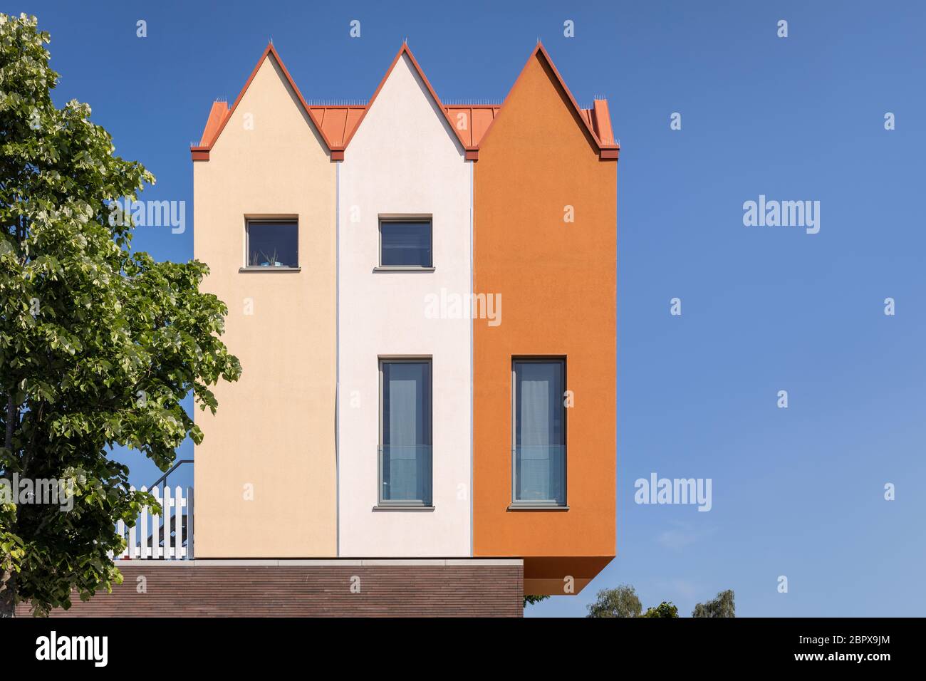 Moderne kleine Wohnhäuser, die auf anderen Häusern in den Niederlanden gebaut werden. Warme farbige Fassaden in verschiedenen Schattierungen. Geometrisch modern ar Stockfoto