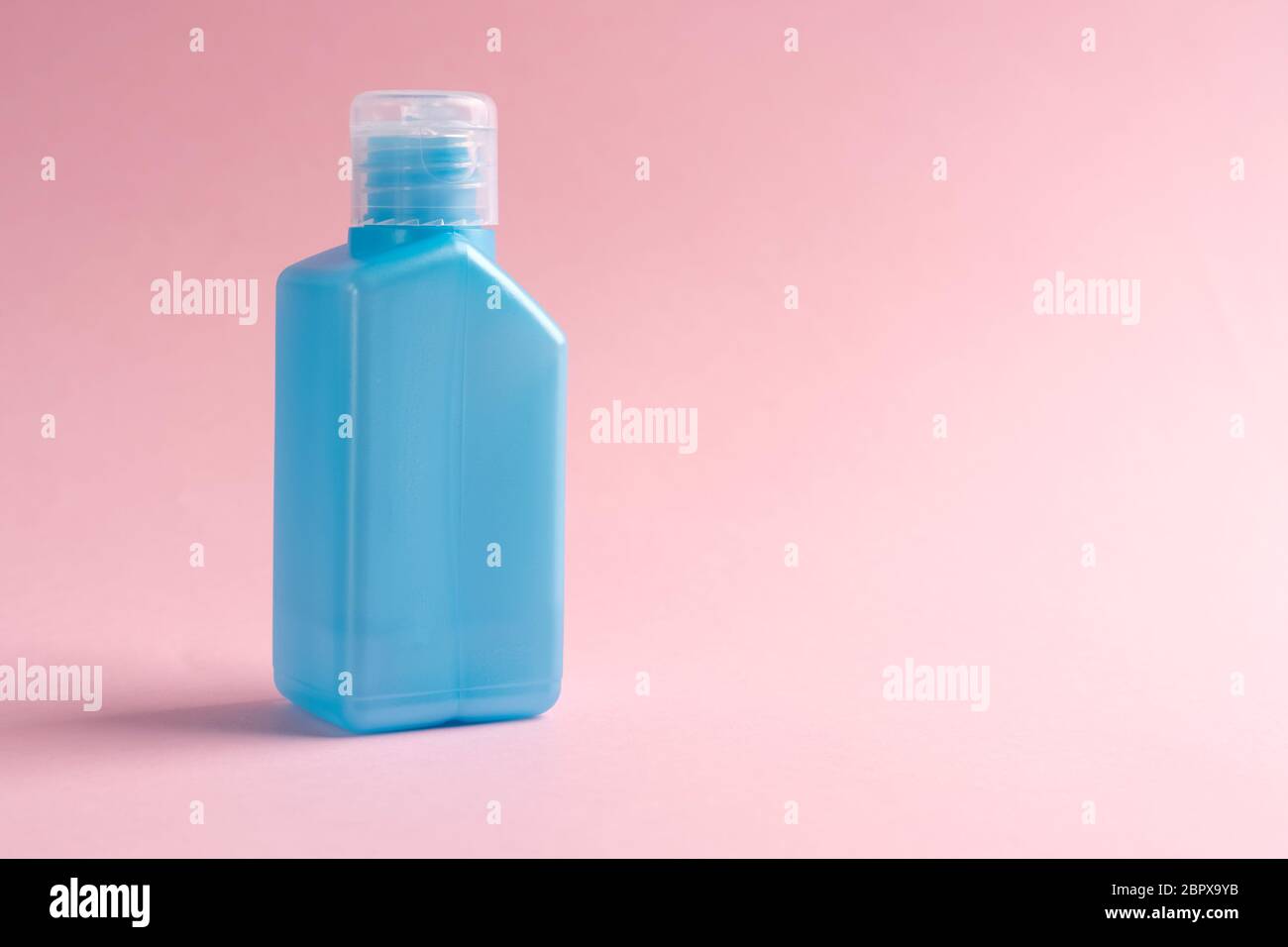 Alkohol Antiseptikum für Hände in einem blauen Kunststoff-Tasche Behälter auf einem rosa Hintergrund. Copyspace. Die Idee der Desinfektion gegen Coronavirus Stockfoto