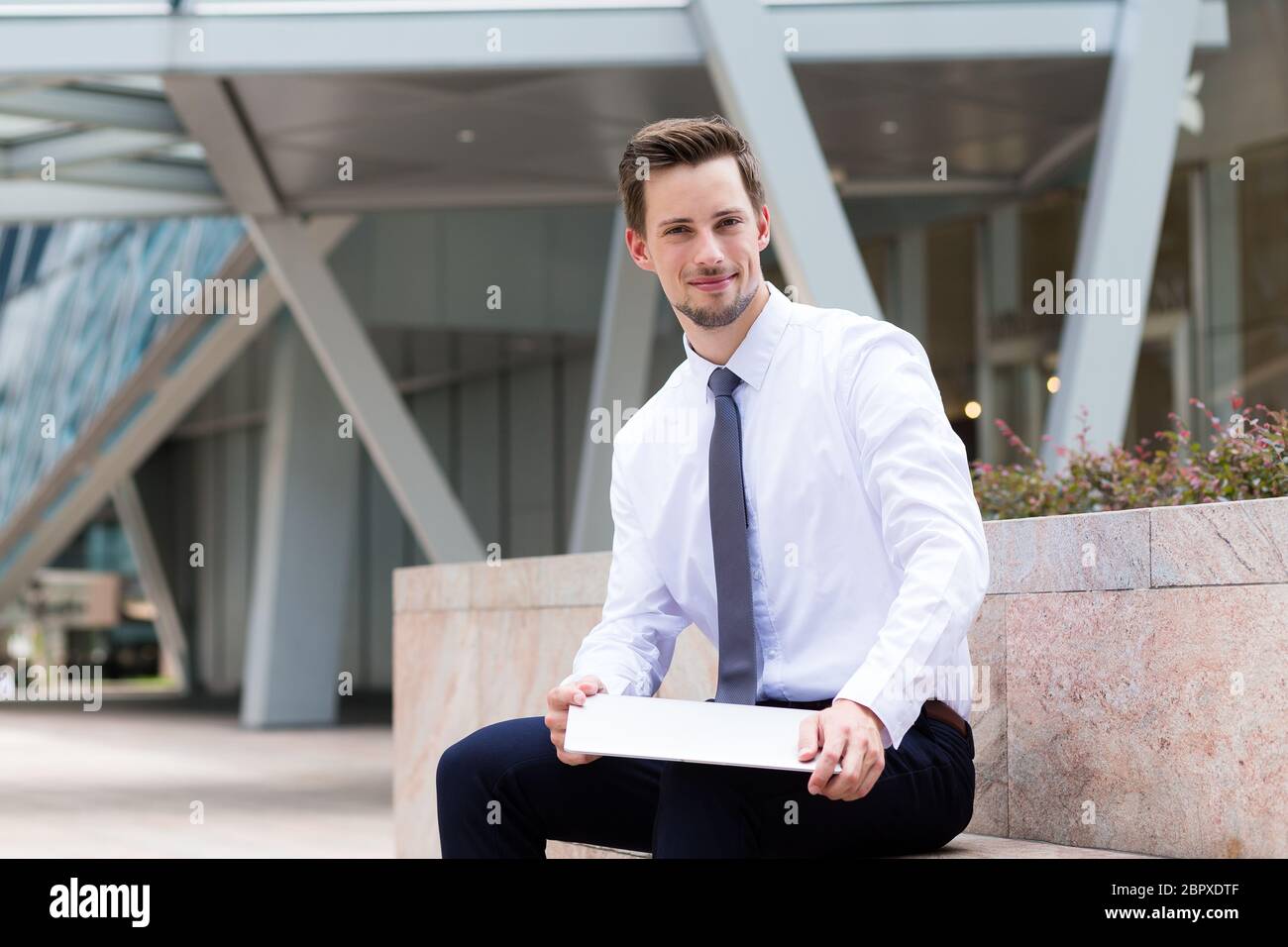 Kaukasischen Geschäftsmann sitzt im Freien und hld mit Laptop-Computer Stockfoto