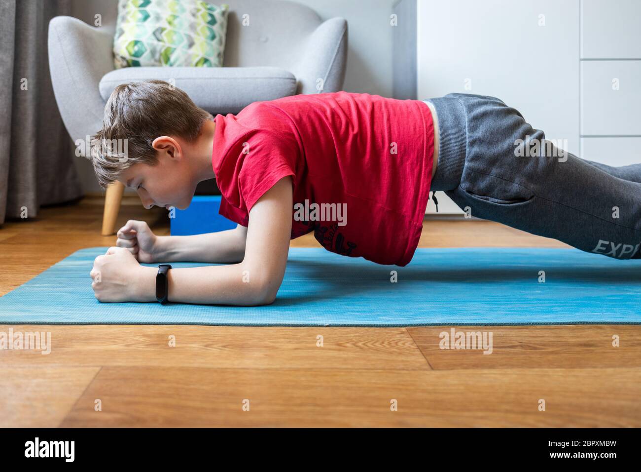 Junge hält Unterarmplanke Pose Yoga zu Hause auf Quarantäne Stockfoto