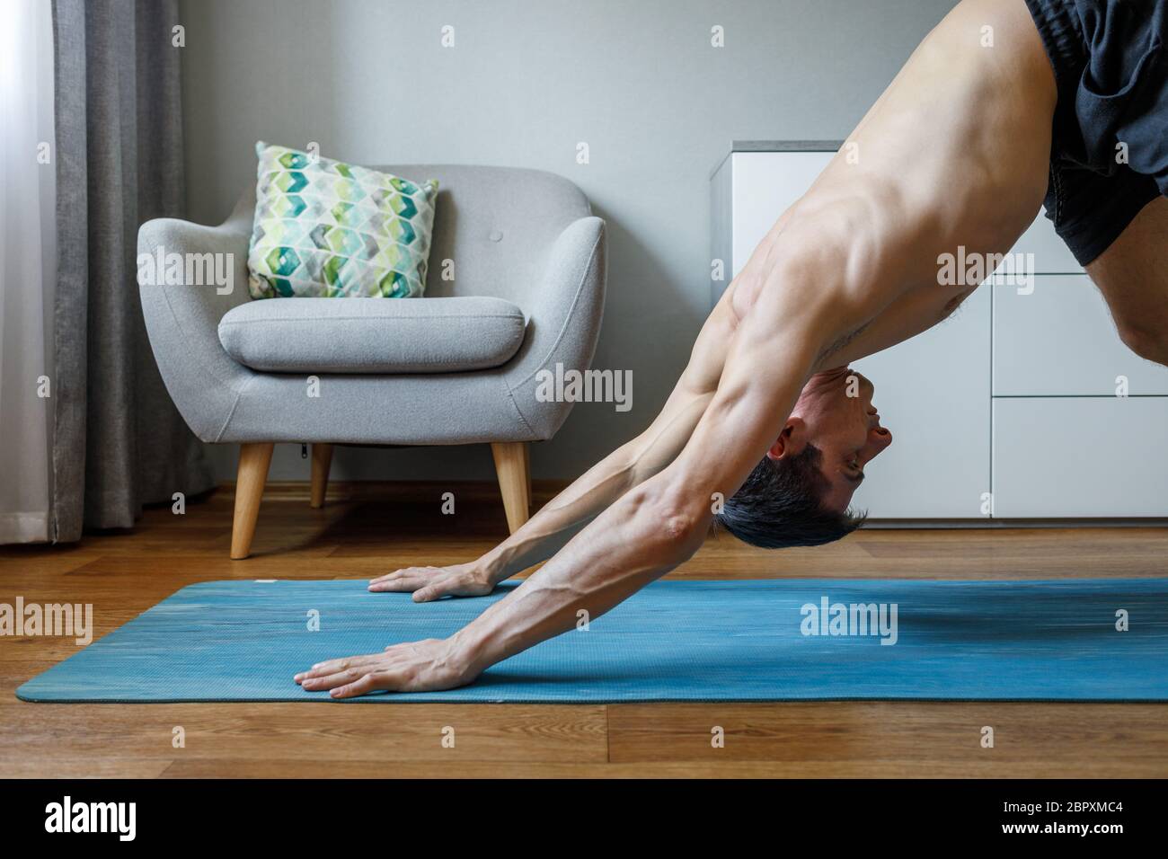 Mann in aufwärts Hund Pose tun vinyasa Fluss zu Hause. Pilates und Yoga zu Hause üben Stockfoto