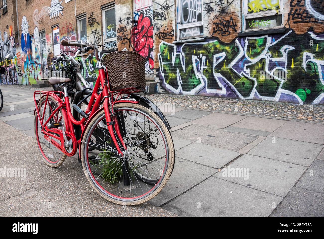 Fahrrad auf der Straße vor Graffiti bedeckten Wand in Shoreditch, London geparkt Stockfoto