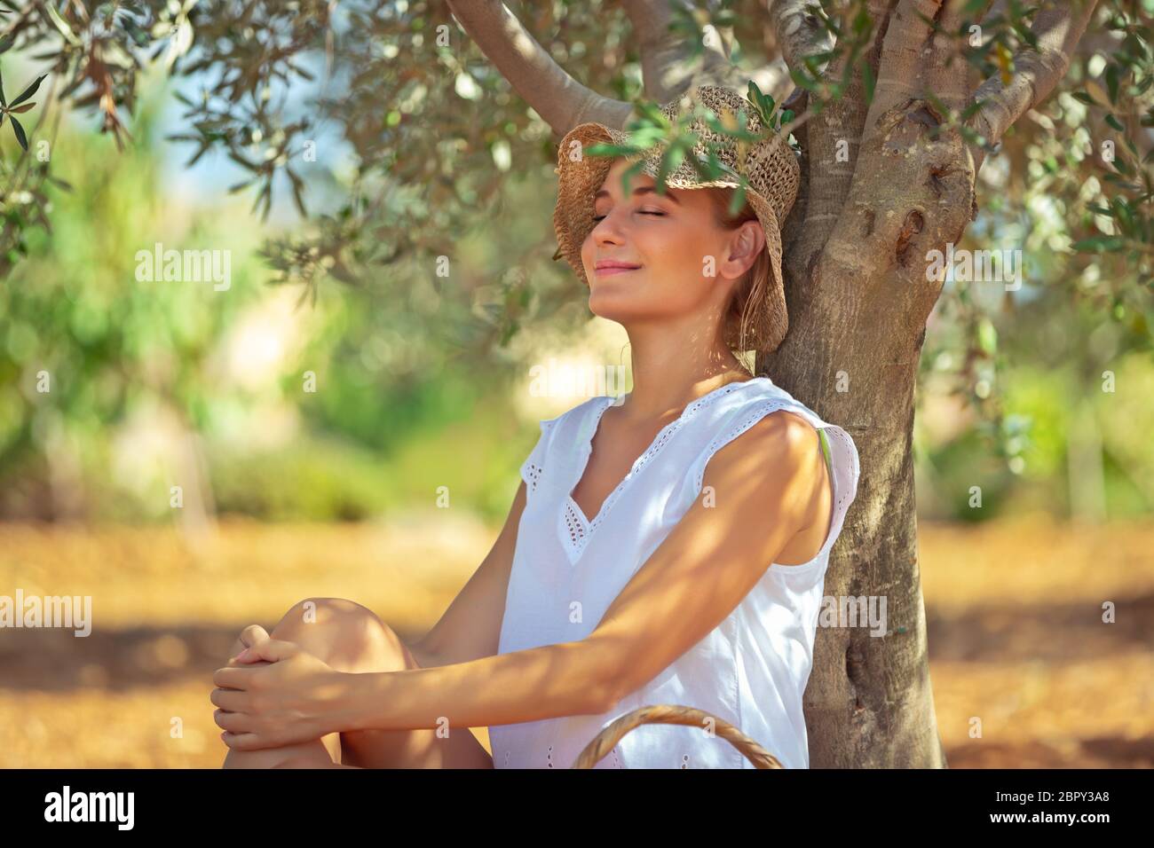 Hübsche Frau Sitzen und Ruhen unter dem Baum im Garten, schöne warmen Frühlingstag, Freizeitgestaltung im Freien, glücklich Frühling Urlaub Stockfoto