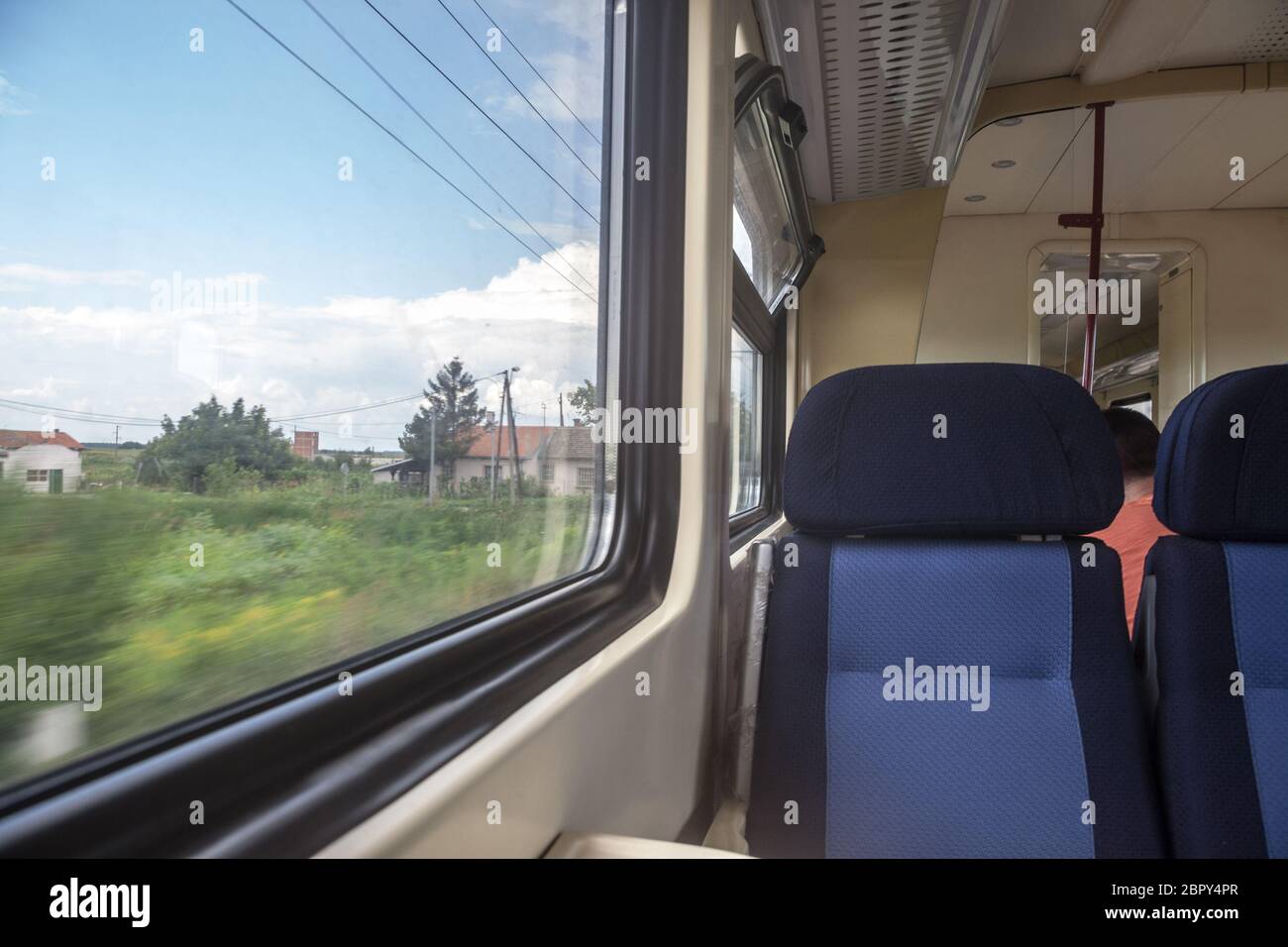 Leere Sitze in einem modernen Regionalzug, im europäischen Stil, auf einer Fahrt in einer Landschaft mit einem Geschwindigkeitsunschärfe-Effekt aus dem Fenster. Bild eines Typi Stockfoto