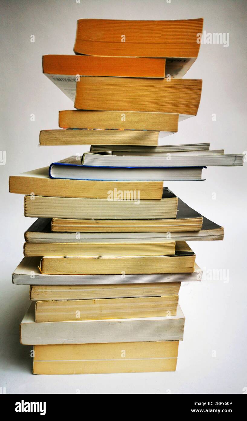 Vertikale Aufnahme einiger alter Bücher, die auf einem weißen Hintergrund aufeinander ragt Stockfoto