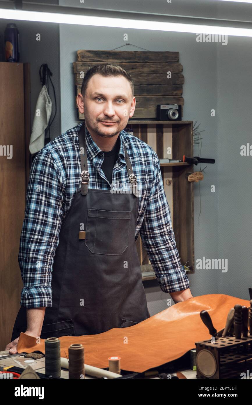 Mann bei der Arbeit mit Leder Textil bei einem Workshop. Männliche portrait. Konzept der Handarbeit Handwerk Herstellung von Lederwaren. Stockfoto