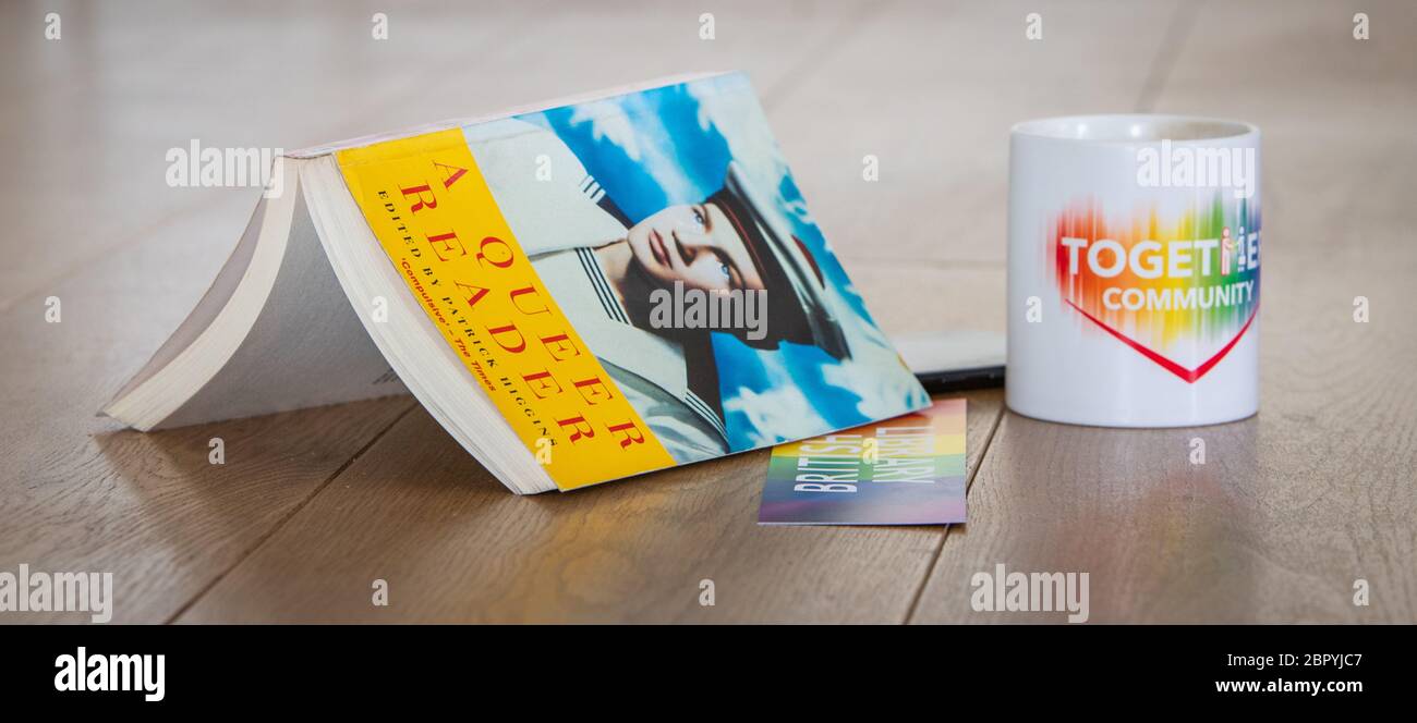 Ein offenes Buch und eine Tasse symbolisieren LGBT-Lesung Stockfoto