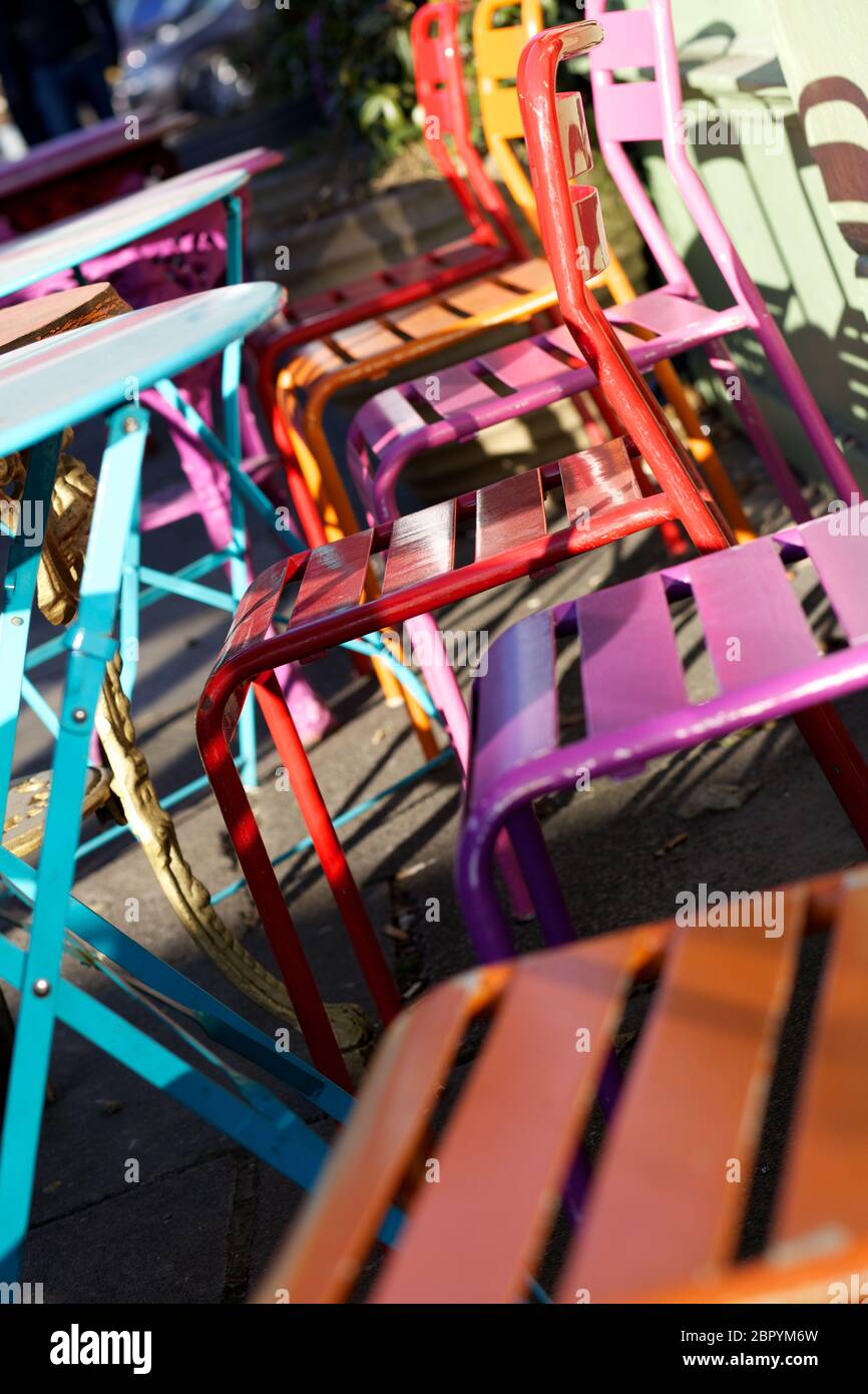 Bunte Metalltische und Stühle außerhalb eines Cafés in der Sonne, Stockfoto