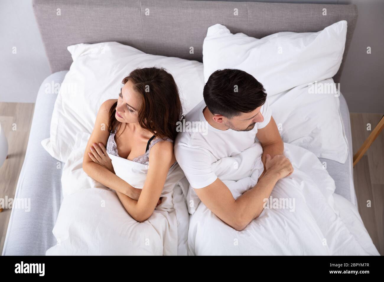 Blick von oben auf die verzweifelten Ehepaar Rücken an Rücken auf dem Bett Stockfoto