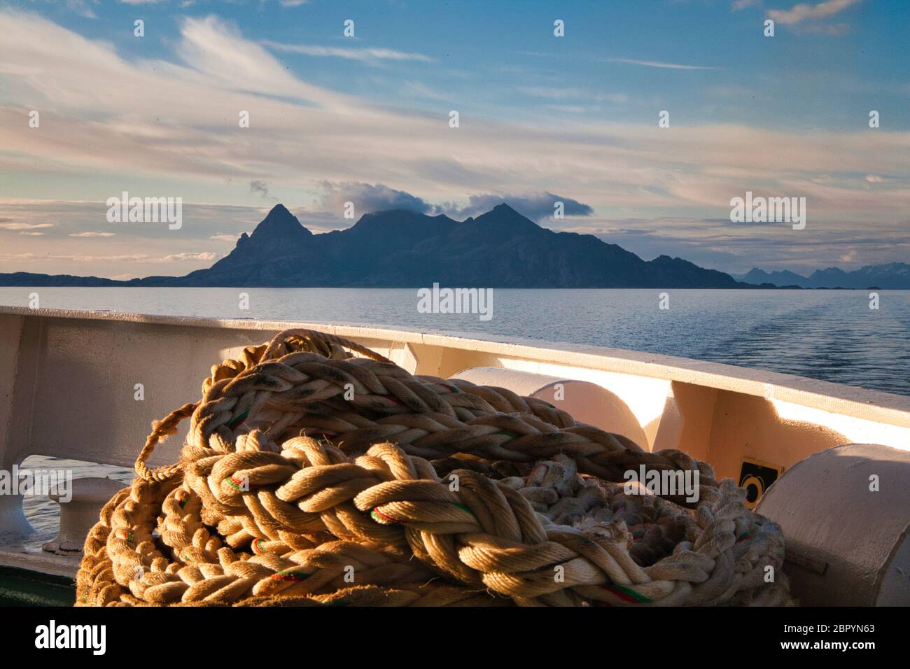 Eine der Lofoten-Inseln oberhalb des Polarkreises im Norden Norwegens, vom Heck eines vorbeifahrenden Schiffes aus gesehen. Schiffsseil im Vordergrund Stockfoto