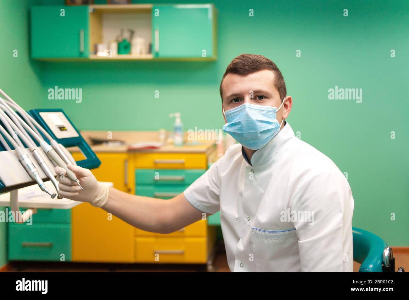 Zahnarzt in einer Maske nimmt einen Bohrer Stockfoto