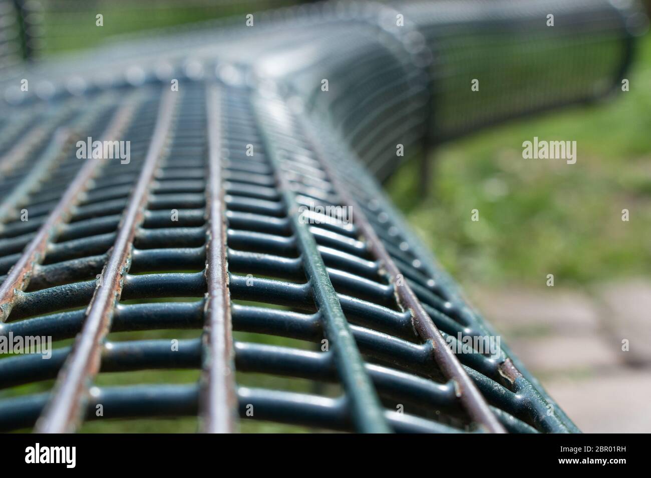 Schräge Ansicht eines grünen Metallparkplatzgitters mit abblätternder Farbe, ausgewählter Fokus Stockfoto