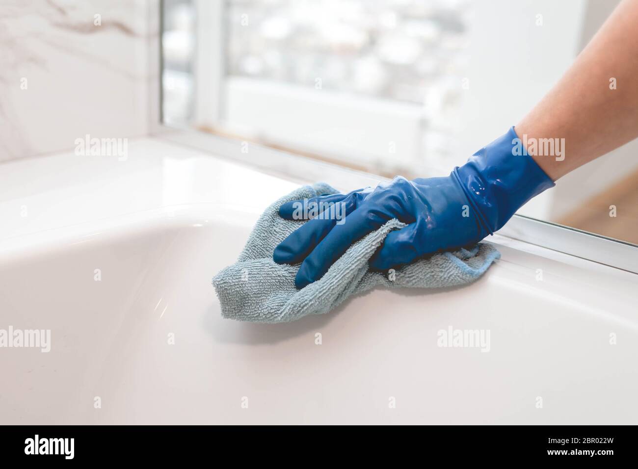 Die Hausfrau in den Handschuhen wäscht das Badezimmer Stockfoto