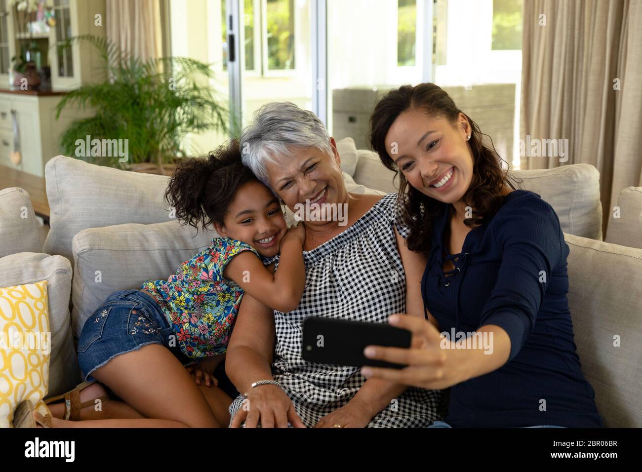 Gemischte Rassenfrau mit ihrer älteren Mutter und ihrer jungen Tochter, die ein Selfie machen Stockfoto