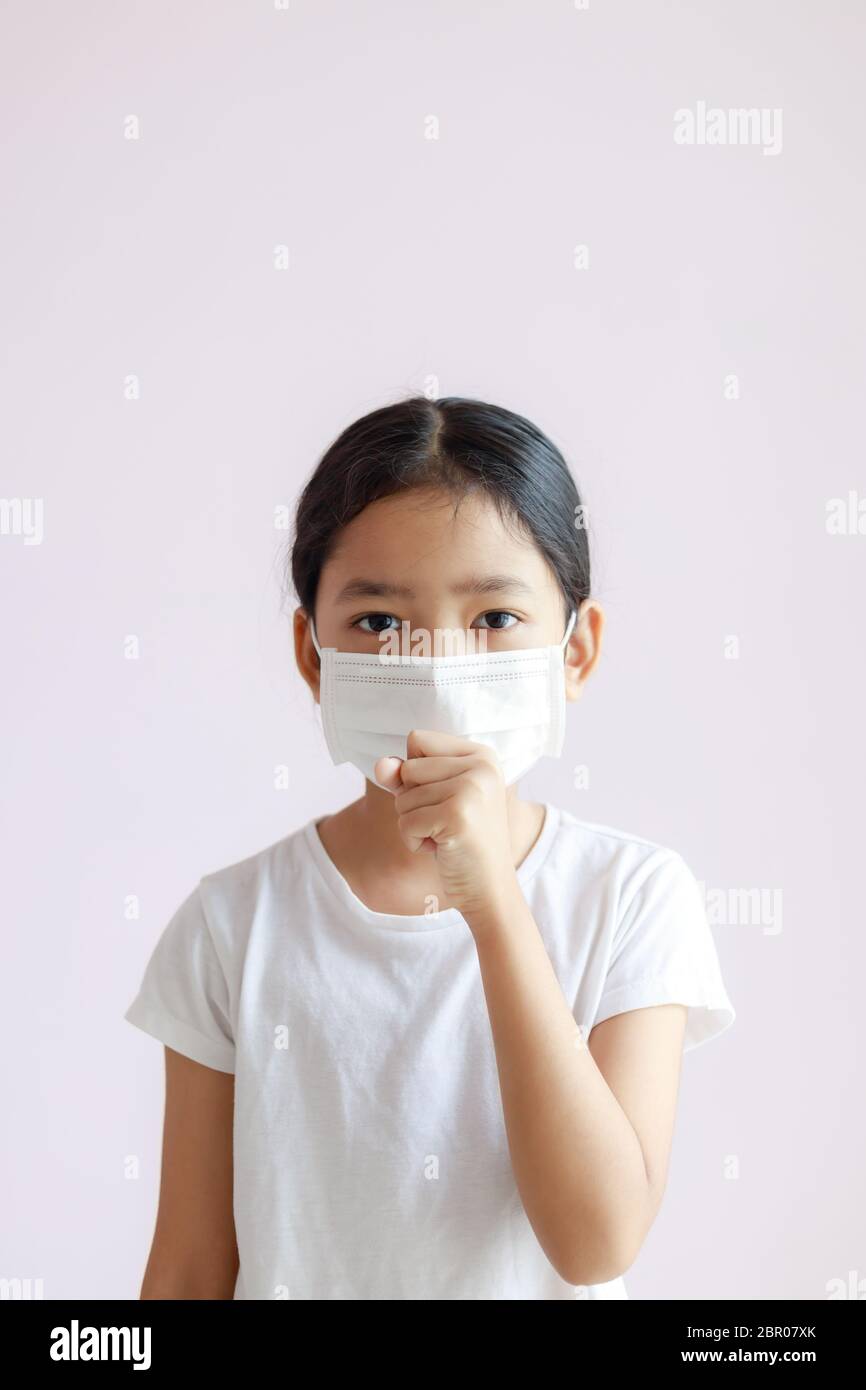 Porträt der asiatischen kleinen Mädchen trägt eine Sanitärmaske und hustet. Die Epidemie der Grippe, des Coronavirus oder COVID-19 und der Krankheit mit Smog. Stockfoto