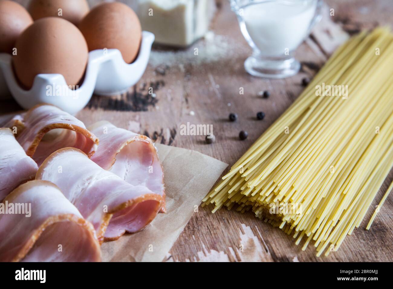 Zutaten für Pasta Carbonara mit Schinken, Käse, Sahne und Eigelb auf hölzernen Tisch. Vorbereitung Spaghetti alla Carbonara. Stockfoto