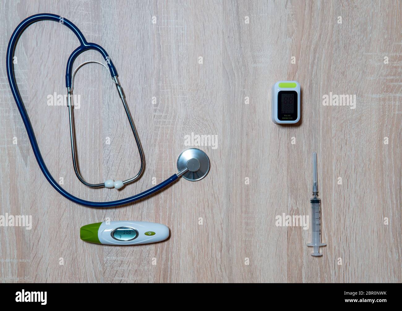 Arztausrüstung-Stethoskop, Thermometer, Oximeter und Spritze auf Holzhintergrund Stockfoto
