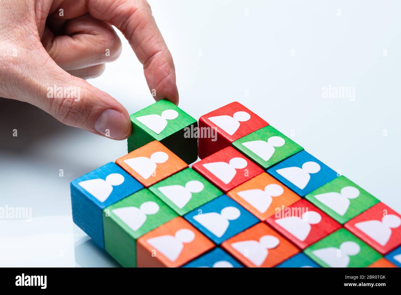 Der Unternehmer Hand grün Cubic Block in der Nähe der Mannschaft der Roten und Grünen Blöcke Stockfoto
