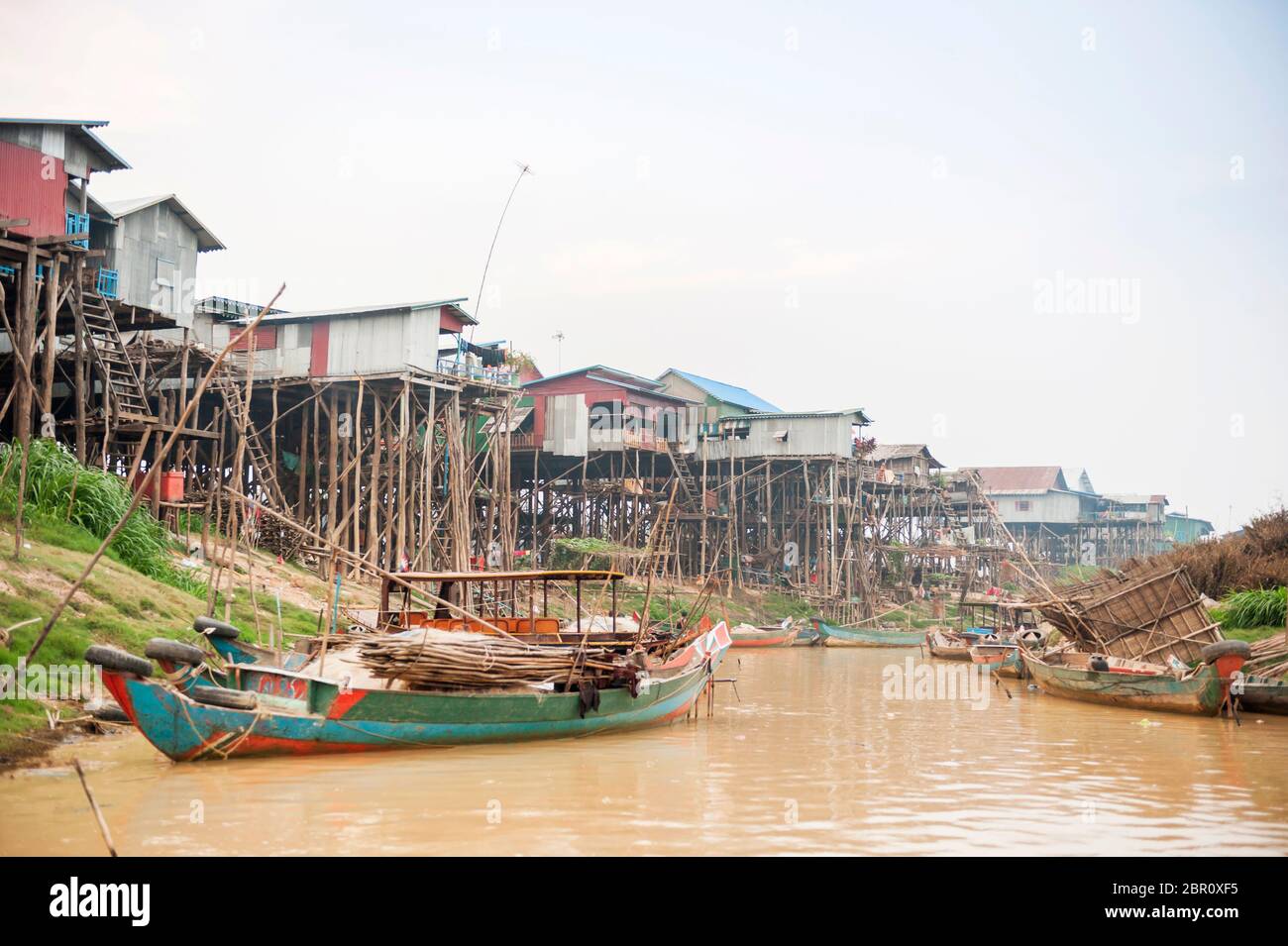 Boote auf dem Fluss mit Häusern auf Stelzen im Hintergrund bei Kampong Phluk, Provinz Siem Reap, Nord-Zentral Kambodscha, Südostasien Stockfoto