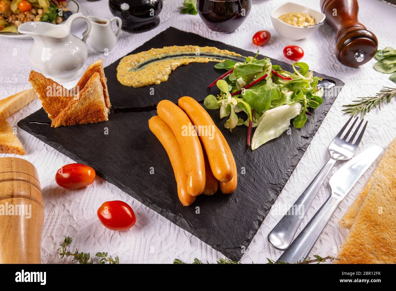 Gekochte Frankfurter Würstchen mit Senf, frischem Salat und Toast auf schiefer Board Stockfoto