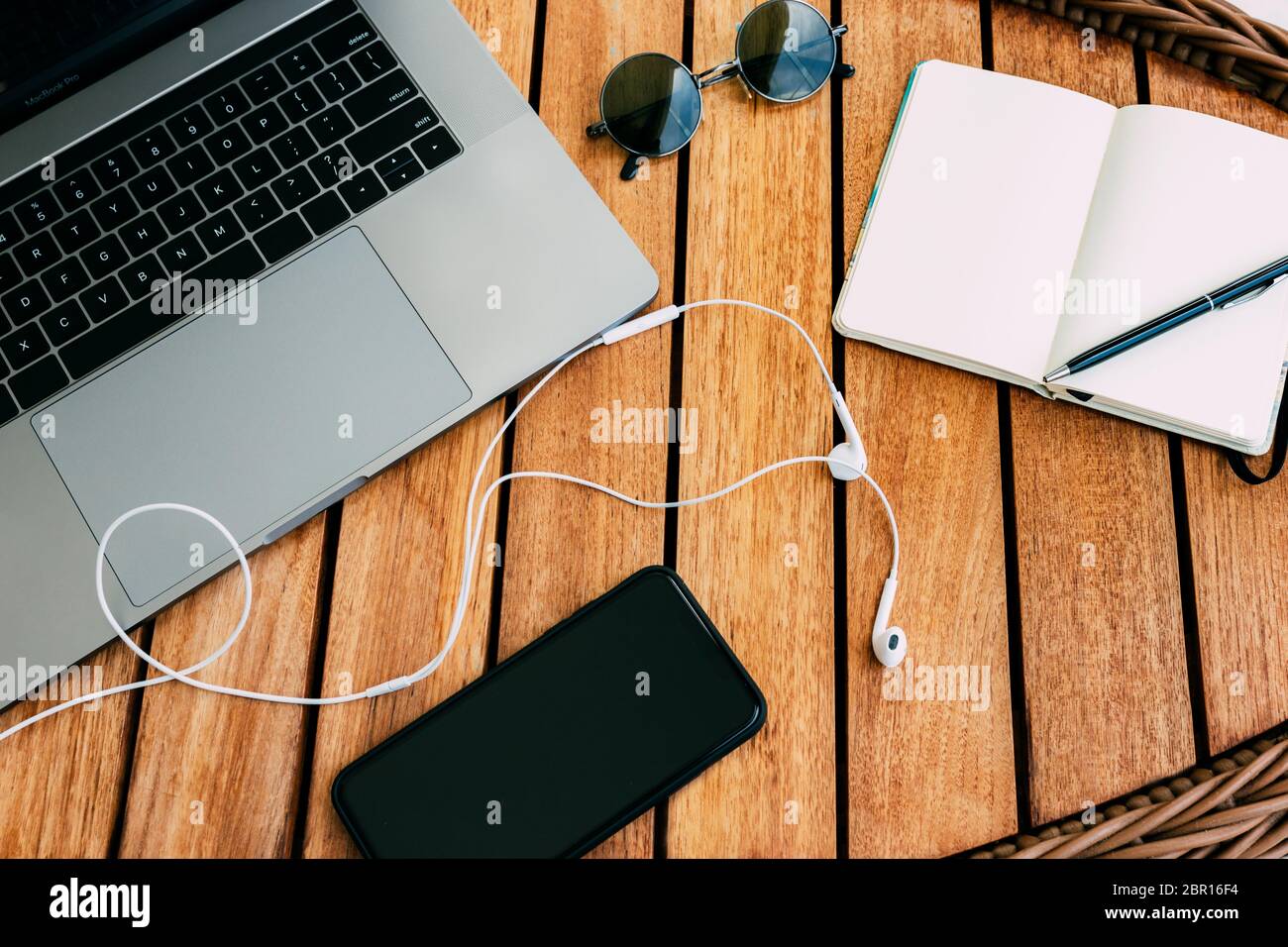 Flacher Lay des Arbeitsplatzes mit Laptop, auf einem braunen Holztisch mit Smartphone eine Tasse Kaffee und ein Notebook für die Aufnahme von Koffern. Business concep Stockfoto