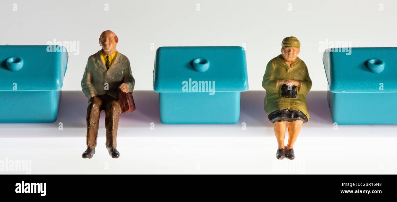 Miniaturfiguren Rentner sitzen zwischen kleinen blauen Häusern Stockfoto