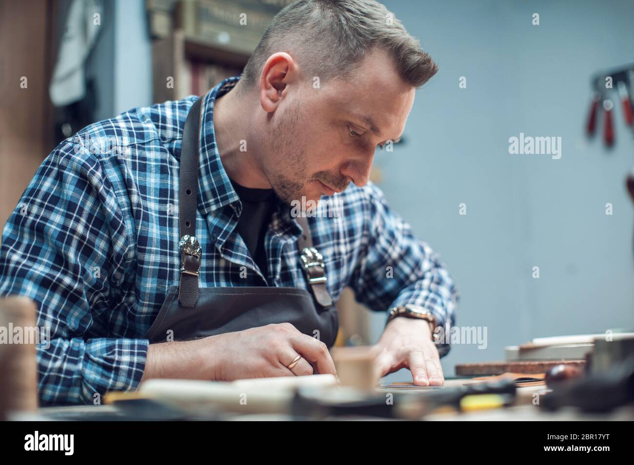 Mann bei der Arbeit mit Leder Textil bei einem Workshop. Craftman schneiden Leder. Konzept der Handarbeit Handwerk Herstellung von Lederwaren. Stockfoto