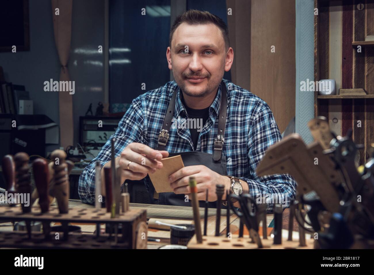 Mann bei der Arbeit mit Leder Textil bei einem Workshop. Männliche portrait. Konzept der Handarbeit Handwerk Herstellung von Lederwaren. Stockfoto