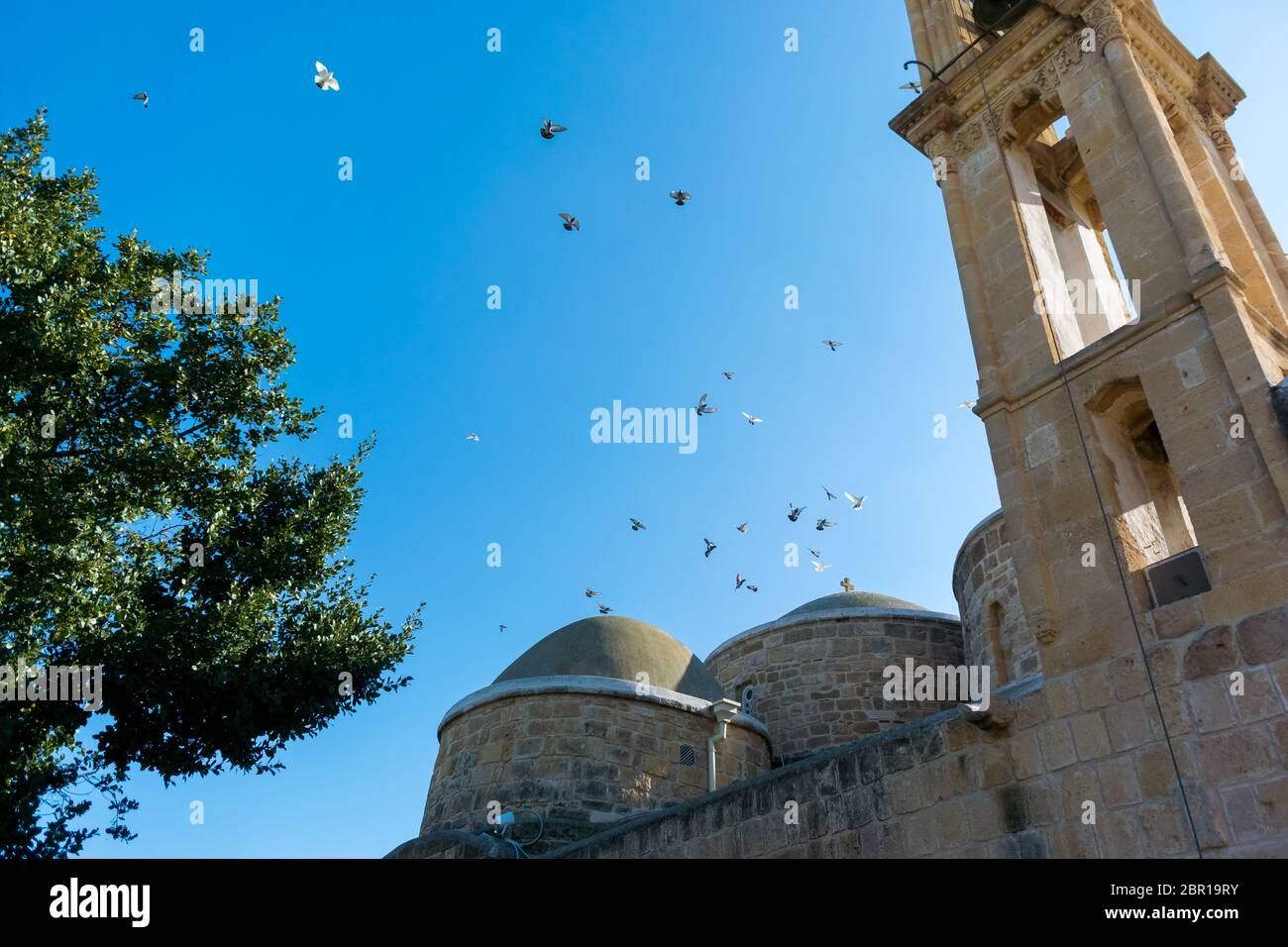 Taubenschar, die über der Kirche der Apostel Barnabas und Hilarion (Agii Varnavas und Ilarionas) in Peristerona, Zypern, schweben Stockfoto
