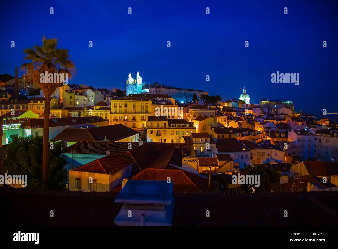 Nachtansicht des Alfama-Viertels und der Santo Estevao-Kirche vom Aussichtspunkt Miradouro das Portas do Sol in Lissabon, Portugal Stockfoto