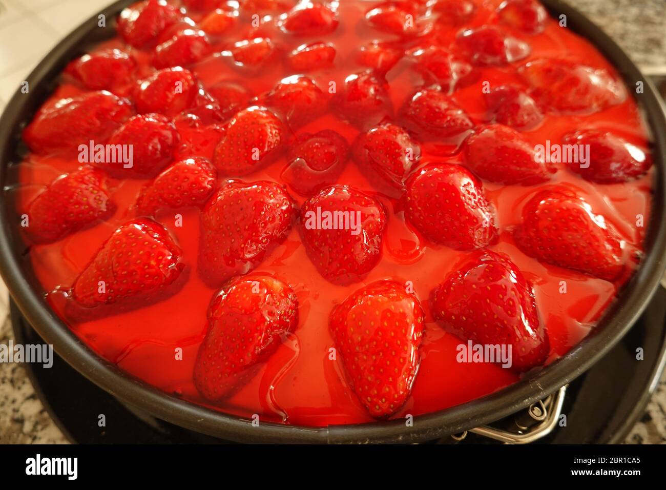 Erdbeerkuchen in einer schwarzen Frühlingsform - Nahaufnahme von Gelee-Fruchtaufständern, Detailansicht eines leckeren frischen, hausgemachten cac mit vielen roten Erdbeeren Stockfoto