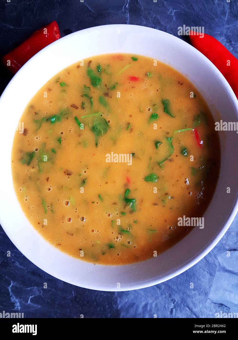 Rote Thai Hühnersuppe in einer weißen Schüssel mit roten Chilis auf Hintergrund Stockfoto