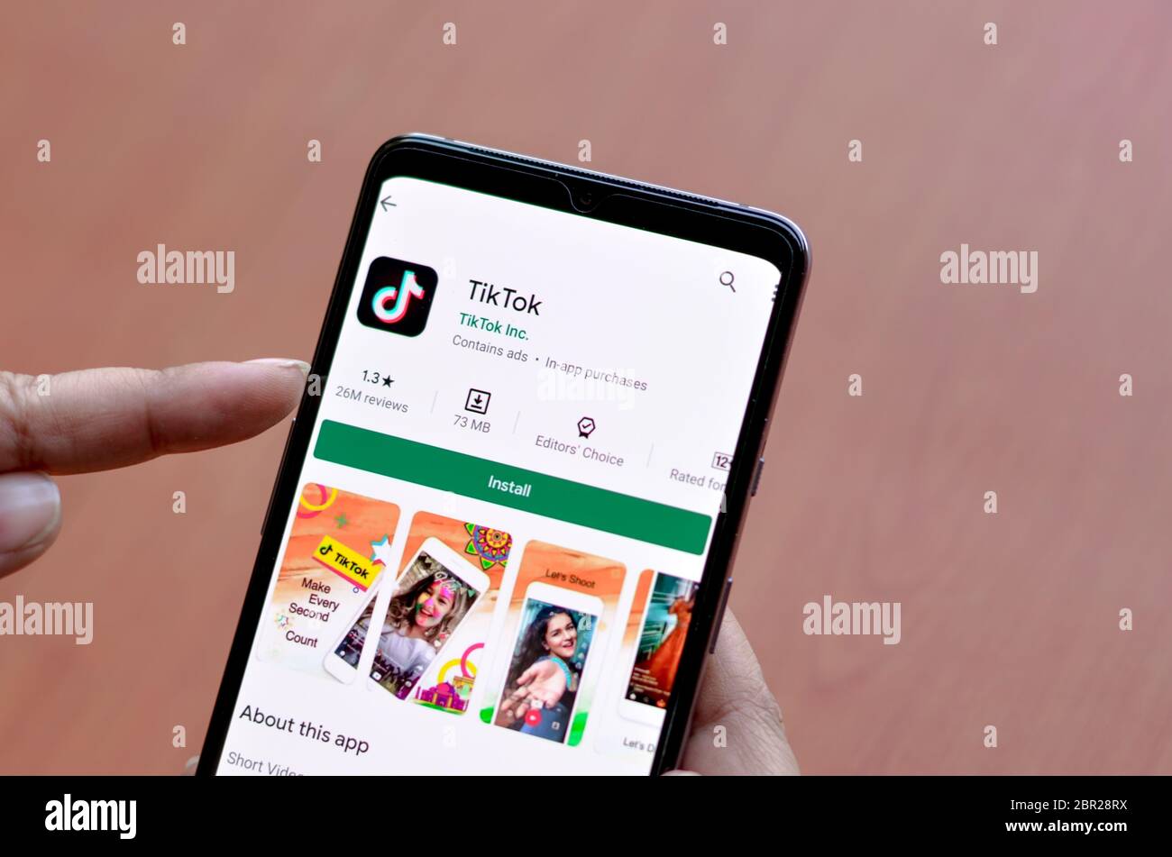 Delhi, Indien, 2020. Frau Installation TikTok mobile App auf einem Smartphone-Bildschirm mit einem hölzernen Hintergrund zeigt Logo der beliebten schnell wachsenden sozialen Stockfoto