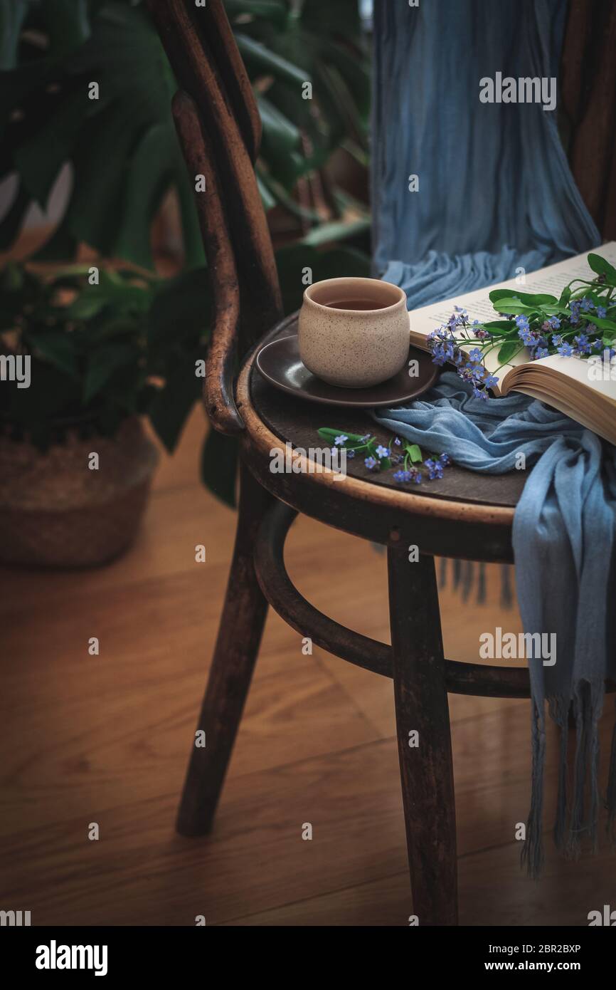 Eine Tasse Tee und ein Buch mit Vergiss mich nicht auf einem Stuhl Stockfoto