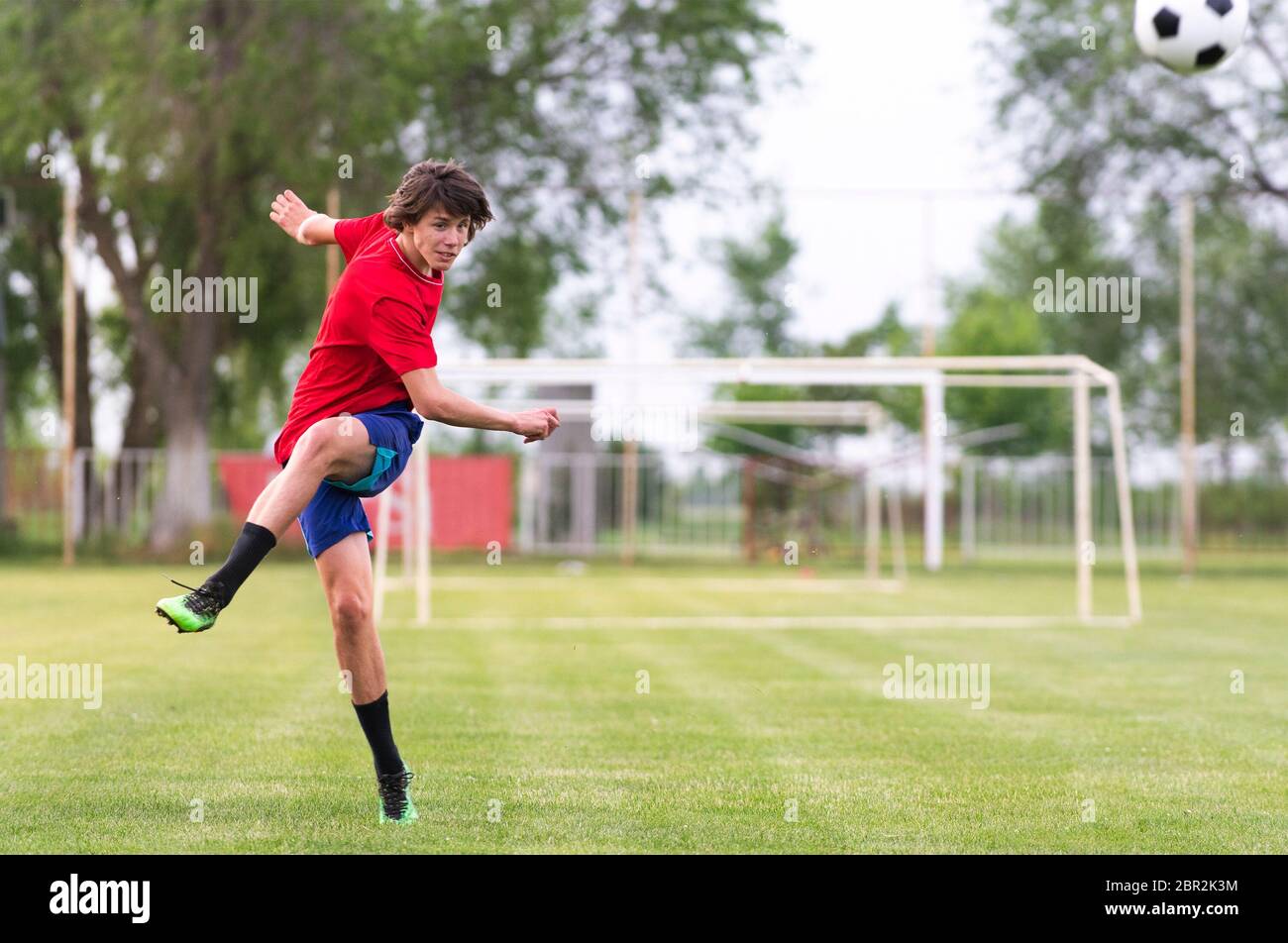 Fußballspieler Teenager kicks Ball in einem Tor Stockfoto