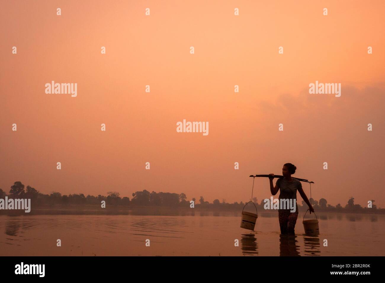 Die junge kambodschanische Frau sammelt Wasser in der Dämmerung in Srah Srang, einem alten Stausee in Angkor. Provinz Siem Reap, Kambodscha, Südostasien Stockfoto