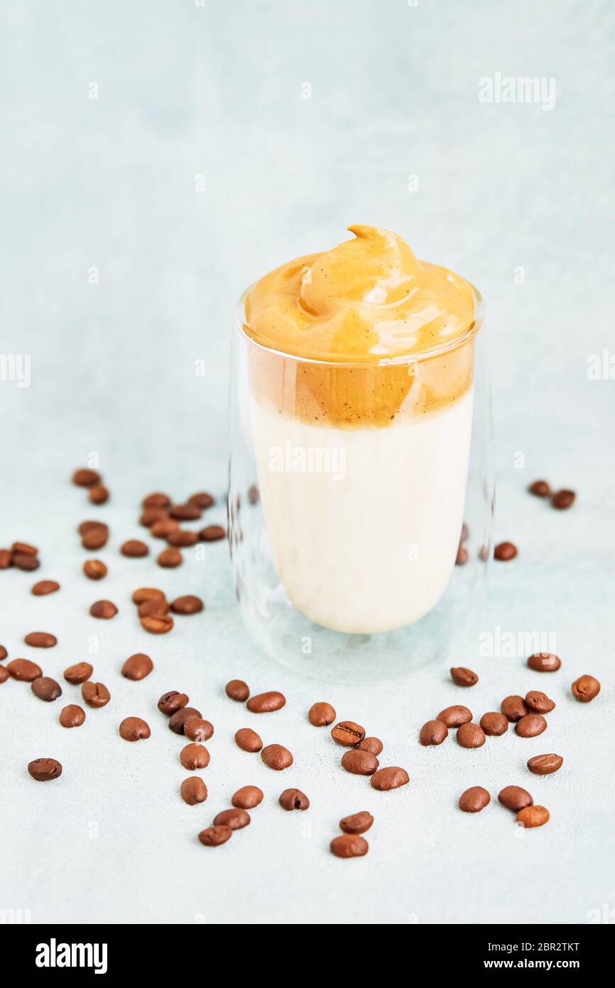 Trendy hausgemachten Dalgona Kaffee in Glas auf blauem Hintergrund. Rezept der beliebten koreanischen Getränk Latte mit Schaum von Instant-Kaffee. DIY, Anleitung. Stockfoto