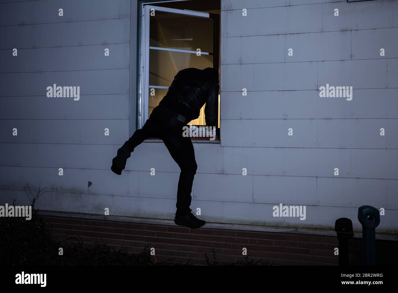 Ansicht der Rückseite ein Einbrecher in ein Haus durch ein Fenster Stockfoto