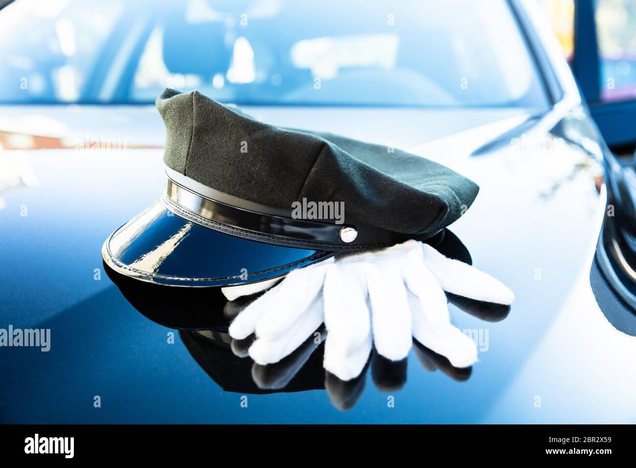 Der schwarze Chauffeur Kappe und ein Paar weiße Hand Handschuhe auf Motorhaube Stockfoto