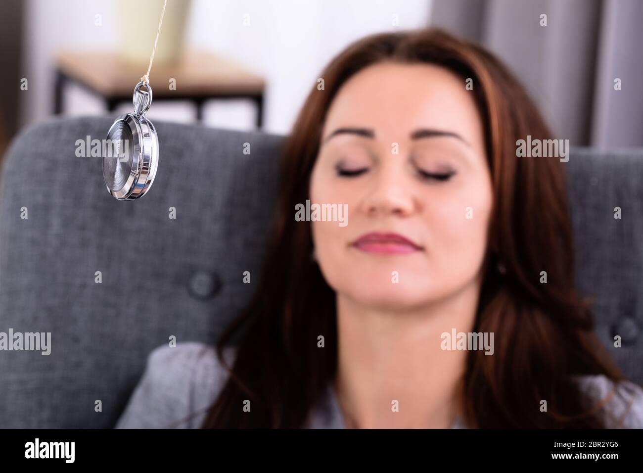 Attraktive junge Frau, beim Sitzen auf dem Sofa zu Hause hypnotisiert Stockfoto