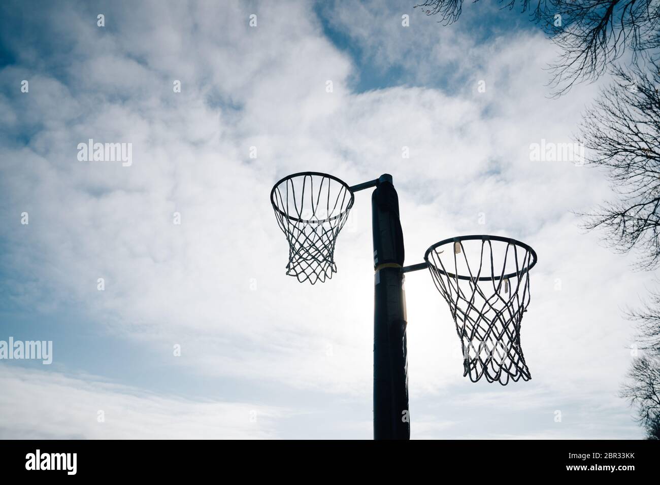 Netball-Torring und -Netz gegen blauen Himmel und Wolken im Hagley Park, Christchurch, Neuseeland. Stockfoto