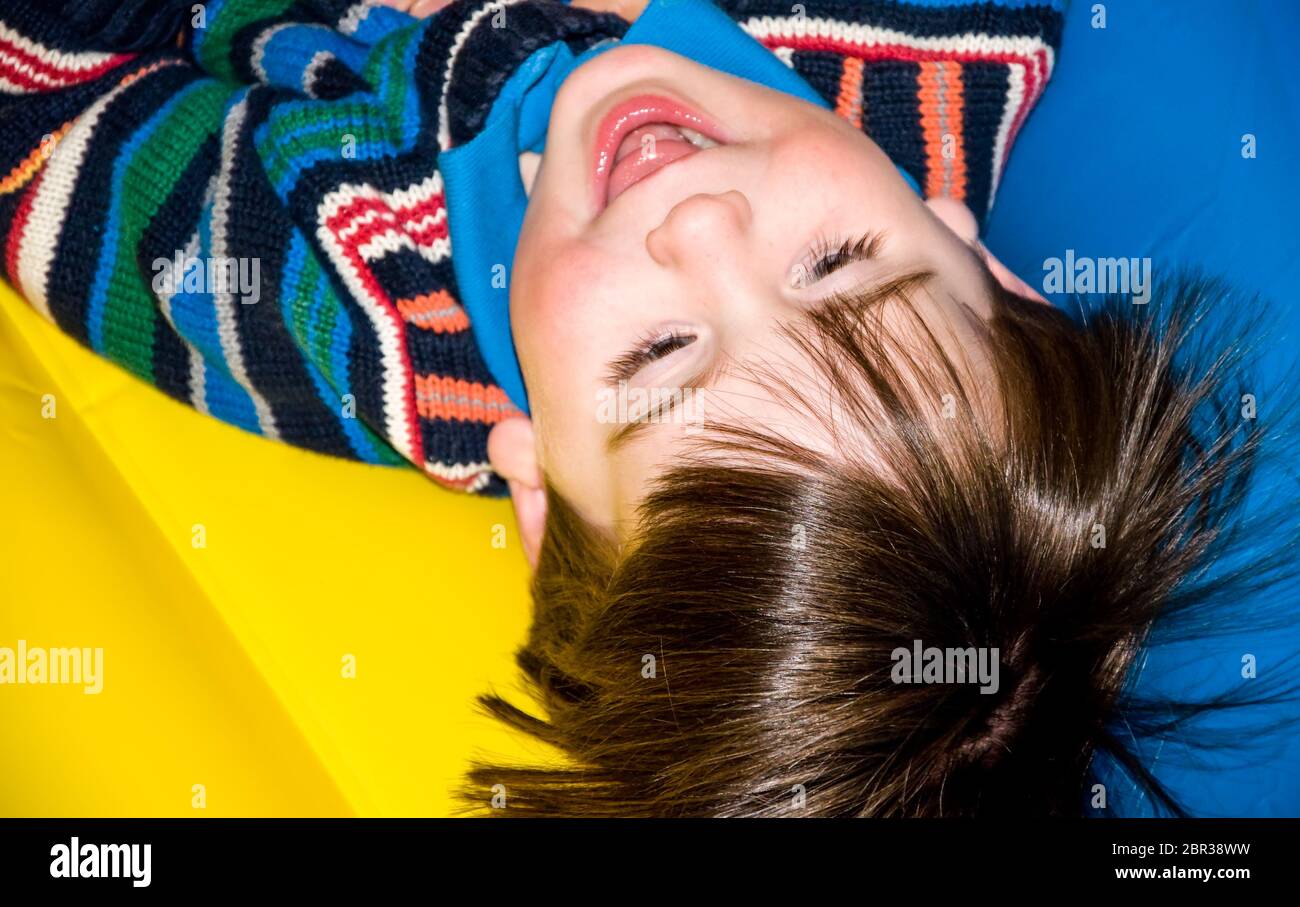 Kleiner Junge auf dem Kopf mit farbenfroher Kleidung. Stockfoto